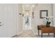 Bright hallway with tiled floors, and a wooden table next to white orchid for an inviting entry at 5103 Shady Stone Pl, Wimauma, FL 33598