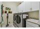 A laundry room with stainless steel washer and dryer and white cabinets at 5103 Shady Stone Pl, Wimauma, FL 33598