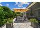 Charming patio area with umbrella covered dining set and manicured landscaping, perfect for outdoor entertaining at 5103 Shady Stone Pl, Wimauma, FL 33598