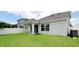 Backyard features a well-maintained lawn, a covered patio, and a white fence, with trees in the background at 5546 Spanish Moss Cv, Bradenton, FL 34203