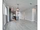 Open-concept living room features modern light fixtures and flows into the kitchen with gray cabinetry at 5546 Spanish Moss Cv, Bradenton, FL 34203