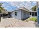 Backyard exterior showcasing paved patio, partial fence, and covered parking connected to the blue home at 5690 82Nd N Ter, Pinellas Park, FL 33781