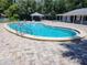 Community pool surrounded by a brick patio with lounge seating, a gazebo, and manicured trees at 802 Brandy Wine Dr # 802, Largo, FL 33771
