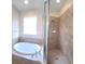 Bright bathroom featuring a soaking tub, shower, and a large window at 8320 Manor Club Cir # 4, Tampa, FL 33647