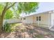 View of the back porch, wood floors, and the home's exterior, with backyard featuring patchy grass and white fencing at 9445 Cardy St, New Port Richey, FL 34654