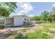 Rear exterior of the home with a wooden deck and stairs, visible AC unit, patchy grass, and a white fence at 9445 Cardy St, New Port Richey, FL 34654