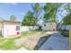 View of the backyard featuring two storage sheds, white fencing, and a partially paved area under a blue sky at 9445 Cardy St, New Port Richey, FL 34654