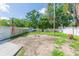 A view of the backyard with patchy grass, white fencing, an American flag, and scattered debris on the ground at 9445 Cardy St, New Port Richey, FL 34654