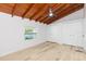 Bedroom with vaulted ceilings, wood beam, new flooring, and large window at 9445 Cardy St, New Port Richey, FL 34654