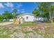 Quaint single-story home with a new deck and white siding nestled among mature trees at 9445 Cardy St, New Port Richey, FL 34654