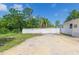 Home exterior with a white fence and gate enclosing the yard, complete with mature trees at 9445 Cardy St, New Port Richey, FL 34654