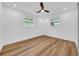 A bright, empty bedroom featuring wood floors, two windows for natural light and a ceiling fan at 9801 56Th N St, Pinellas Park, FL 33782