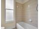 Bright bathroom featuring a tub with beige tiles and natural light from a window at 10510 Lithia Estates Dr, Lithia, FL 33547