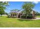 Inviting front exterior with a large lawn, mature trees, dormer windows and a welcoming porch at 10510 Lithia Estates Dr, Lithia, FL 33547