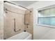 Bathroom featuring neutral tile surround, shower head, shower caddy, grab bar, and window at 1116 W Kirby St, Tampa, FL 33604