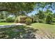 Landscaped home exterior featuring a carport, driveway, lawn, bushes, tree, and pink flowers at 1116 W Kirby St, Tampa, FL 33604
