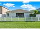 This backyard features a well-maintained lawn, white picket fence, and a screened lanai, perfect for relaxation at 11309 Langworth Hill Ln, Riverview, FL 33579