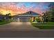 Charming home featuring a three-car garage, beautiful landscaping, and a gorgeous sunset at 11714 Tetrafin Dr, Riverview, FL 33579