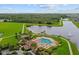 Aerial view of the community pool, surrounding landscaping, and lake on a sunny day at 11714 Tetrafin Dr, Riverview, FL 33579