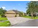 View of a three car garage and a paved driveway of a single-Gathering home with manicured landscaping at 12439 Bristol Commons Cir, Tampa, FL 33626