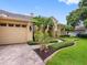 Beautifully landscaped home featuring lush greenery and a charming, paver-tiled driveway leading to a two-car garage at 12439 Bristol Commons Cir, Tampa, FL 33626