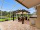 Covered outdoor kitchen featuring grill, sink, dining table and chairs and a pergola overlooking a pond at 12439 Bristol Commons Cir, Tampa, FL 33626
