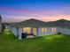 This home features a well-maintained backyard with lush green grass and a covered patio at sunset at 13105 Fruitville Way, Riverview, FL 33579