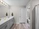 Bathroom featuring double sinks, quartz countertops, hardwood floors and white cabinets at 13105 Fruitville Way, Riverview, FL 33579