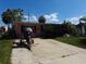 A single-story home with a brick facade, trailer, and motorcycle under a bright blue sunny sky at 13710 Frances Ave, Hudson, FL 34667