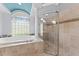 Bright bathroom with walk-in shower, soaking tub, tiled walls, and a glass block window at 1553 Canopy Oaks Blvd, Palm Harbor, FL 34683