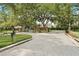 Gated entrance featuring brick walls, mature trees, and lush landscaping at 1553 Canopy Oaks Blvd, Palm Harbor, FL 34683