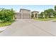 Spacious home with a large driveway leading to an attached three-car garage and well-maintained landscaping at 1553 Canopy Oaks Blvd, Palm Harbor, FL 34683