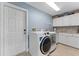 Well-organized laundry room with front loading washer/dryer, ample storage, and tiled backsplash at 1553 Canopy Oaks Blvd, Palm Harbor, FL 34683
