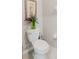 Close up of a standard toilet, with simple artwork, and a vase of lilacs on top of the tank at 17156 Yellow Pine St, Wimauma, FL 33598