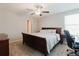 Primary bedroom suite featuring soft carpeting, a queen-sized sleigh bed, ceiling fan and an attached desk and chair at 17156 Yellow Pine St, Wimauma, FL 33598