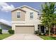 Two-story home featuring a two-car garage, neutral color scheme, manicured lawn, and small shrubs at 17156 Yellow Pine St, Wimauma, FL 33598