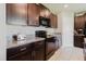A kitchen featuring dark wood cabinetry, granite countertops, and modern appliances, well-lit and inviting at 17156 Yellow Pine St, Wimauma, FL 33598