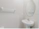 Small powder room featuring a white pedestal sink, oval mirror, and simple design aesthetic at 17156 Yellow Pine St, Wimauma, FL 33598