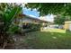 View of a backyard featuring a screened-in patio, lush lawn, and a storage shed at 17807 Fallowfield Dr, Lutz, FL 33549