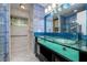 Bright bathroom featuring a double sink vanity with glass countertop and blue tiled walls at 17807 Fallowfield Dr, Lutz, FL 33549