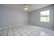 Bright bedroom features tile flooring, a window, and neutral-colored walls at 17807 Fallowfield Dr, Lutz, FL 33549