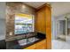 Updated kitchen showcasing stainless steel sink, granite counters, tile backsplash, and view to the pool at 17807 Fallowfield Dr, Lutz, FL 33549