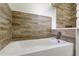 Clean bathroom featuring a white bathtub, wood-look tile accent, and a modern faucet at 1868 Lombardy Dr, Clearwater, FL 33755