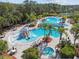 Aerial view of a resort-style community pool with a waterslide, palm trees, lounging chairs, and spa at 20244 Merry Oak Ave, Tampa, FL 33647