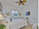 Bright bedroom featuring a plush white bed, light wood floors, a ceiling fan and backyard view at 2292 Sifield Greens Way # 59, Sun City Center, FL 33573