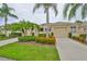 Charming one-story home with well-manicured landscaping, vibrant flowers, and towering palm trees at 2292 Sifield Greens Way # 59, Sun City Center, FL 33573