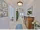 Inviting hallway with light floors and walls featuring decorative dresser, large mirror, and white floral accents at 2292 Sifield Greens Way # 59, Sun City Center, FL 33573
