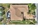 Aerial view of a house with a brown roof, screened-in lanai, lush landscaping and a brick driveway at 2359 Emerald Lake Dr, Sun City Center, FL 33573
