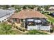 Aerial view of the backyard showing a screened-in lanai, lush landscaping, patio furniture and mature trees at 2359 Emerald Lake Dr, Sun City Center, FL 33573