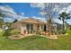 Well-manicured backyard with a screened lanai, stone pathway, lush grass, and decorative landscaping at 2359 Emerald Lake Dr, Sun City Center, FL 33573